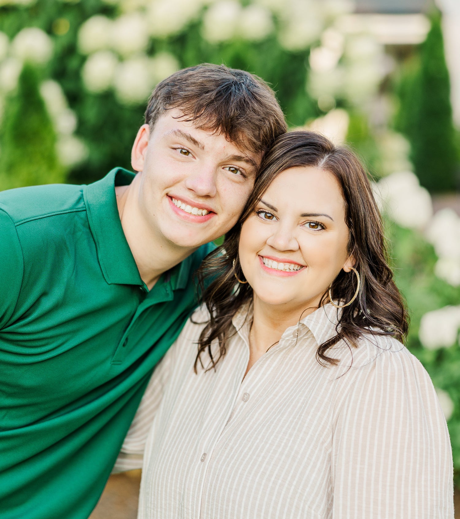 Two people standing together with a blurred floral background
